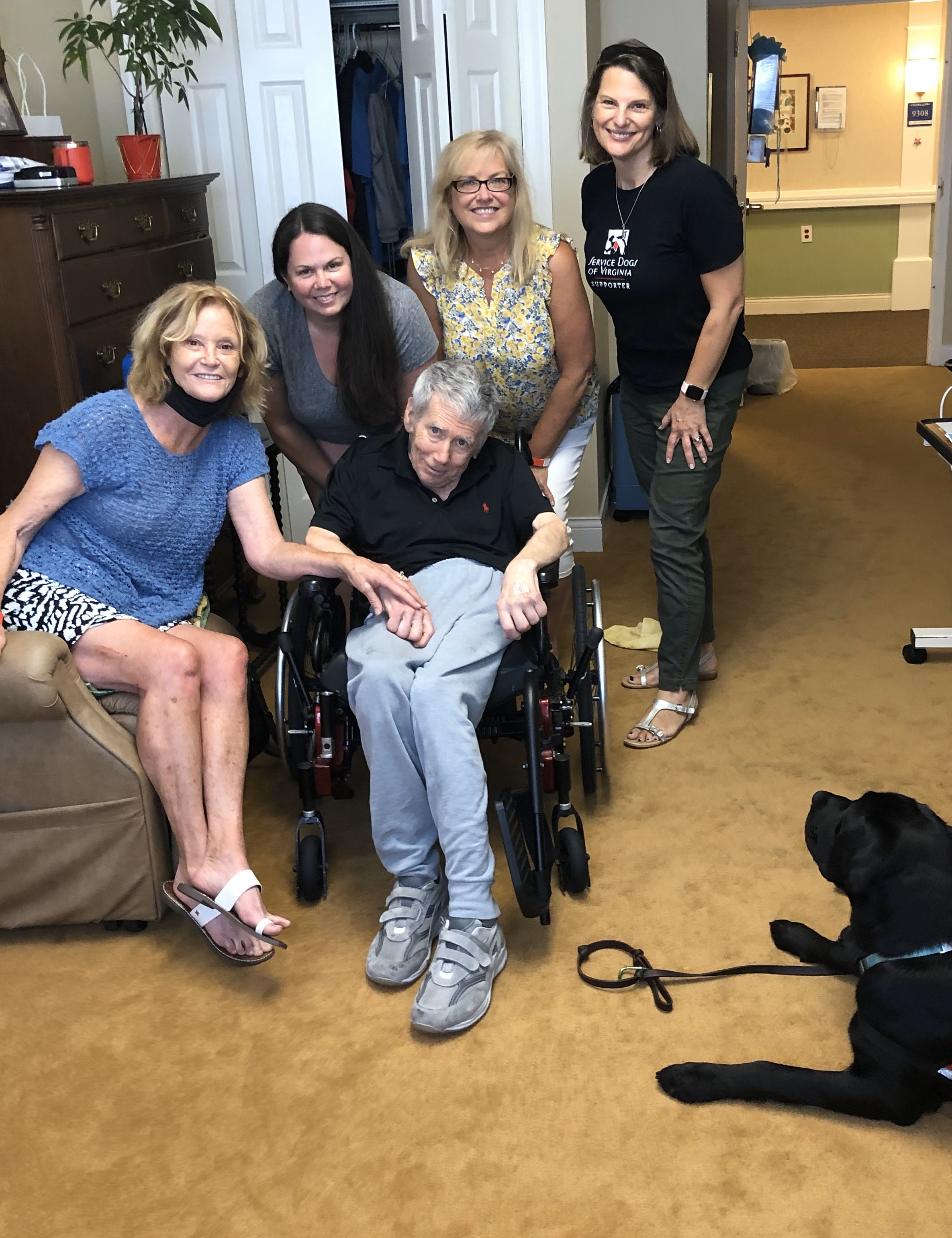 A group of friends posing joyfully with a person in a wheelchair